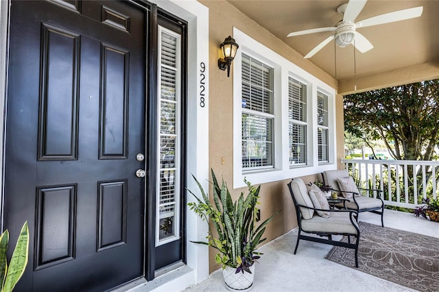 property entrance with ceiling fan, a porch, and stucco siding