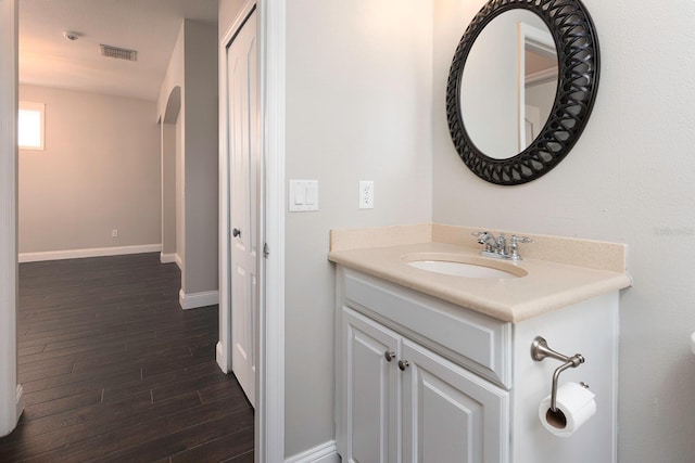 bathroom with vanity, wood finished floors, visible vents, and baseboards