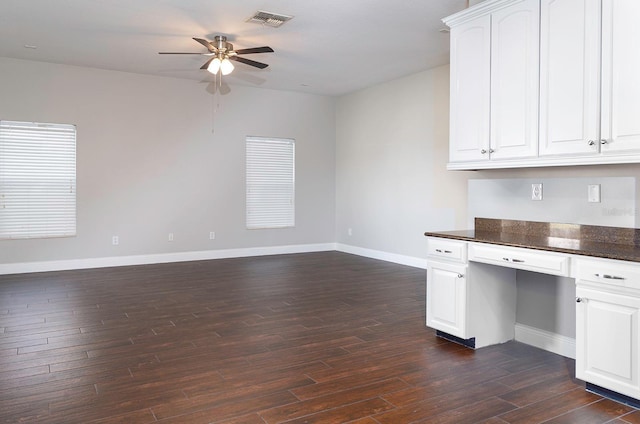 kitchen with dark wood-type flooring, a ceiling fan, white cabinets, baseboards, and built in desk