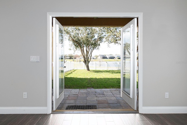 doorway to outside featuring baseboards and wood finished floors