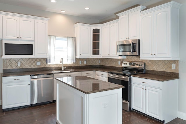 kitchen with dark wood-style floors, appliances with stainless steel finishes, a sink, and white cabinets