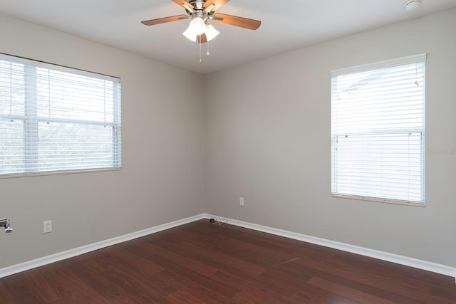 unfurnished room with a ceiling fan, plenty of natural light, baseboards, and dark wood-type flooring