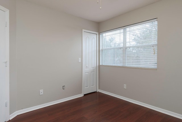 spare room with baseboards and dark wood finished floors