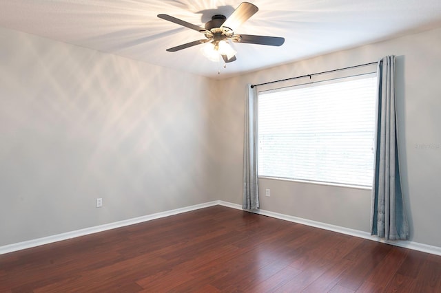 unfurnished room featuring baseboards, dark wood finished floors, and a ceiling fan