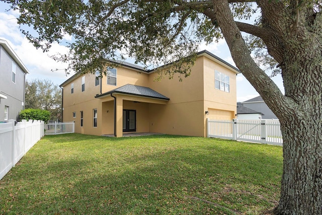 back of property featuring a gate, a fenced backyard, a lawn, and stucco siding