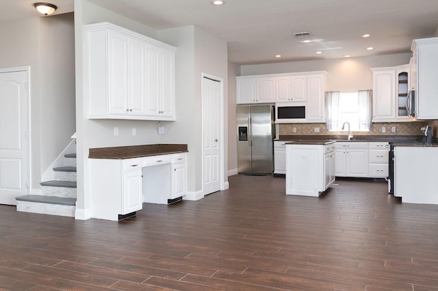 kitchen with stainless steel appliances, dark wood-type flooring, dark countertops, and visible vents