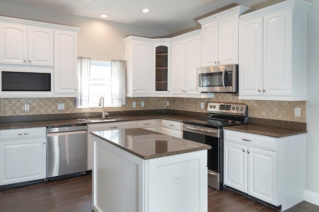 kitchen with stainless steel appliances, dark wood-type flooring, a sink, white cabinets, and tasteful backsplash