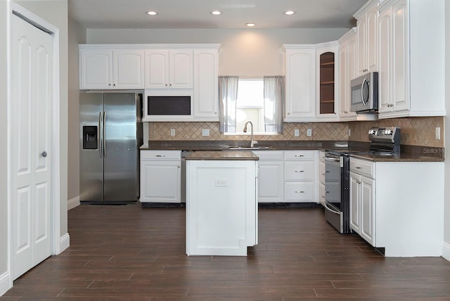 kitchen featuring dark countertops, appliances with stainless steel finishes, white cabinets, and a sink