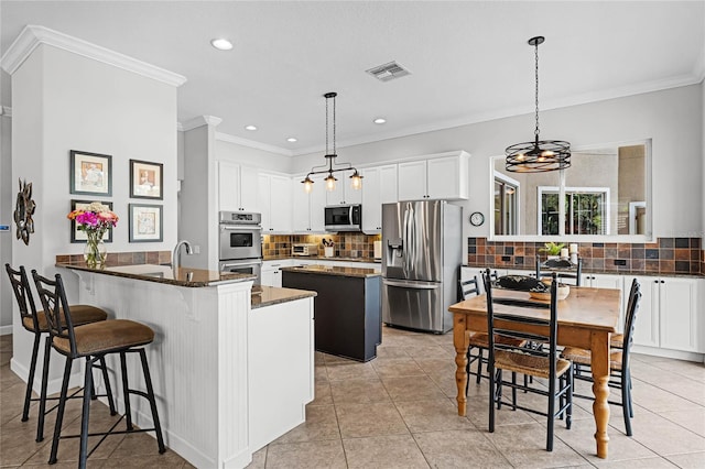 kitchen with visible vents, ornamental molding, decorative backsplash, a peninsula, and stainless steel appliances