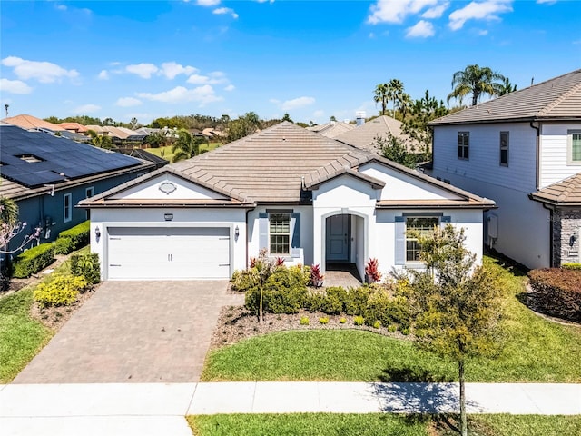 ranch-style home featuring stucco siding, a front lawn, a tile roof, decorative driveway, and an attached garage