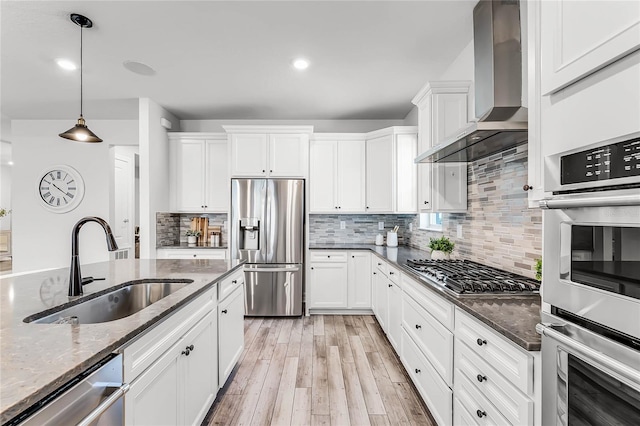 kitchen with backsplash, appliances with stainless steel finishes, wall chimney exhaust hood, and a sink