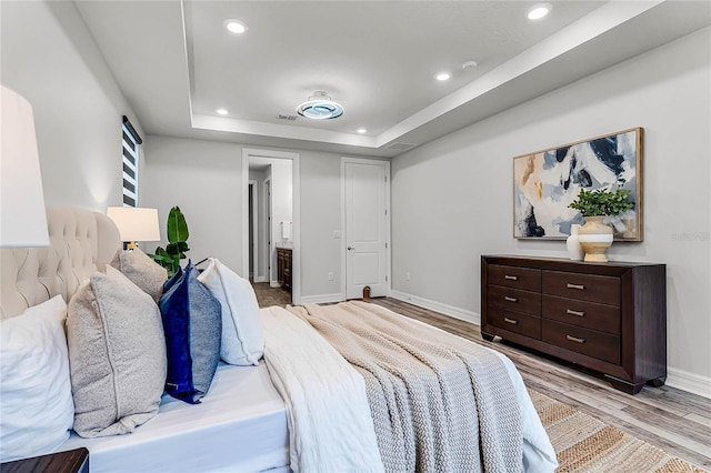 bedroom with recessed lighting, a raised ceiling, baseboards, and wood finished floors