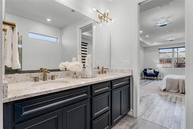 bathroom with double vanity, wood finished floors, visible vents, and a sink