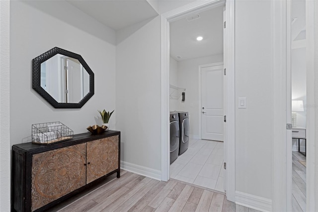 hall with visible vents, baseboards, independent washer and dryer, and light wood finished floors