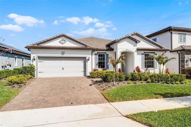 view of front of house featuring a garage, decorative driveway, stucco siding, and a tile roof