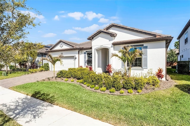 single story home featuring a garage, a front yard, driveway, and stucco siding