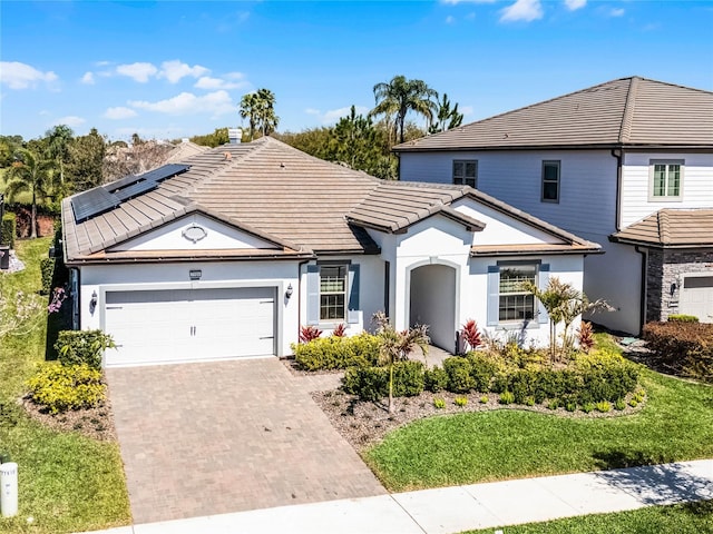 traditional-style house with stucco siding, a tiled roof, decorative driveway, and a garage