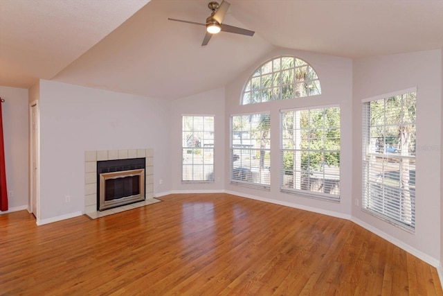 unfurnished living room with lofted ceiling, a wealth of natural light, a fireplace, and light wood-style flooring