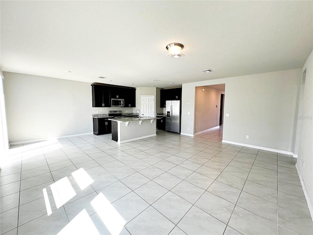 interior space with light countertops, appliances with stainless steel finishes, open floor plan, a sink, and dark cabinetry