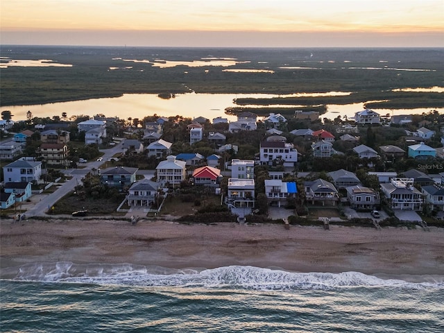 aerial view at dusk with a water view and a residential view