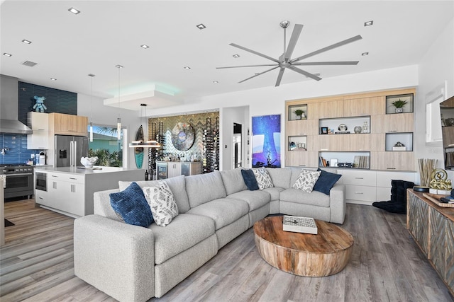 living room with light wood-type flooring, visible vents, a ceiling fan, and recessed lighting