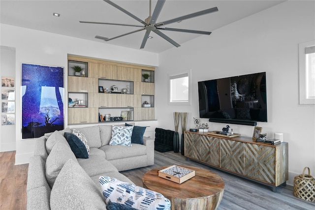 living room with wood finished floors, visible vents, and a ceiling fan