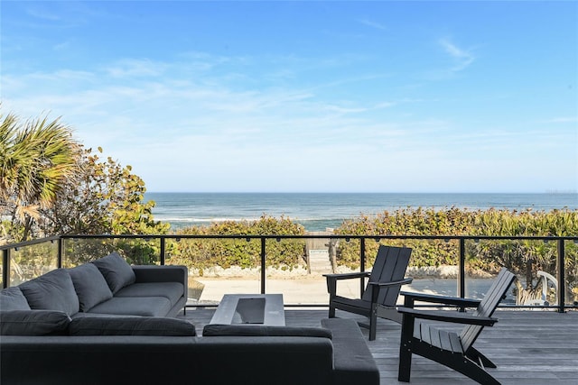 wooden deck featuring a water view, an outdoor hangout area, and a view of the beach