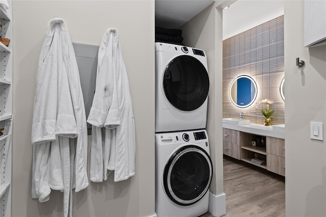 laundry room with stacked washer / dryer, a sink, and light wood finished floors