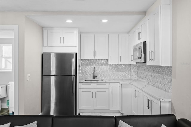 kitchen featuring stainless steel appliances, white cabinets, a sink, and decorative backsplash