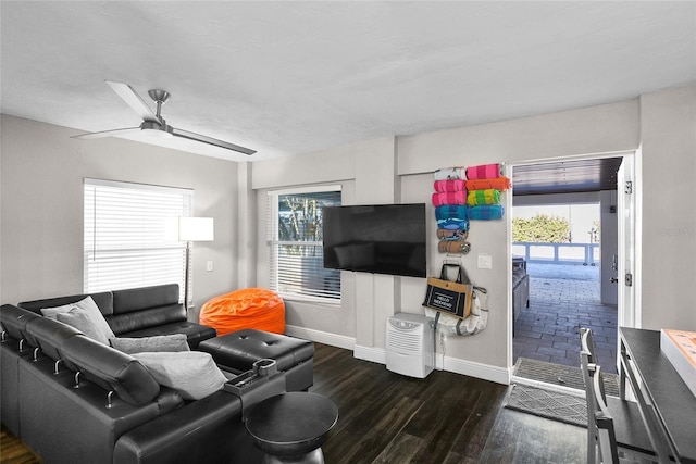 living room with dark wood-style floors, plenty of natural light, baseboards, and a ceiling fan