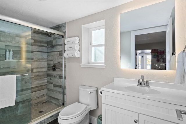 bathroom featuring toilet, a stall shower, a textured wall, and vanity