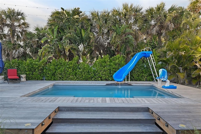 view of swimming pool featuring a water slide and a deck