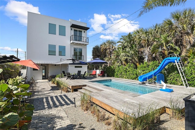 back of property with a patio, an outdoor pool, a balcony, and stucco siding