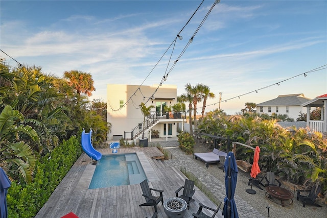 exterior space featuring a deck, an outdoor fire pit, stairway, and a water slide