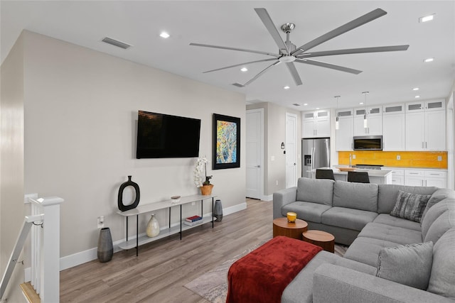 living area with recessed lighting, a ceiling fan, baseboards, visible vents, and light wood-style floors