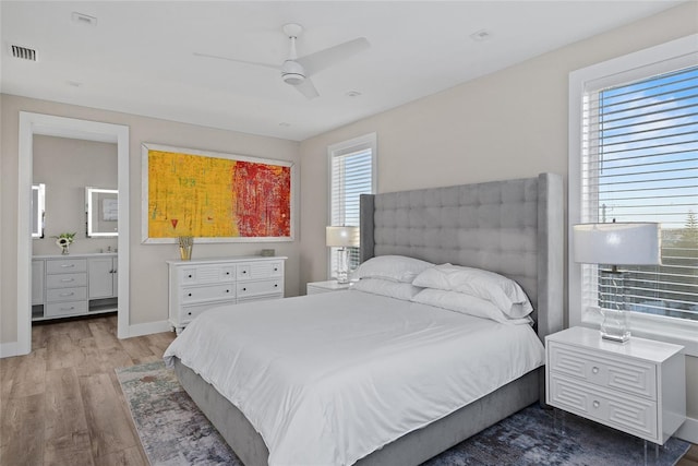 bedroom with baseboards, visible vents, connected bathroom, ceiling fan, and wood finished floors