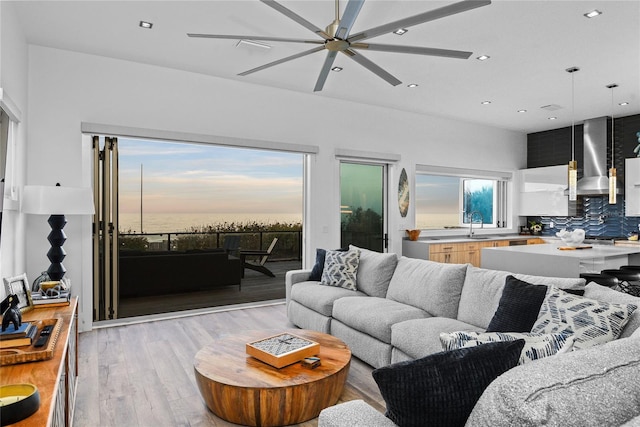 living area featuring light wood-style floors, a ceiling fan, and recessed lighting