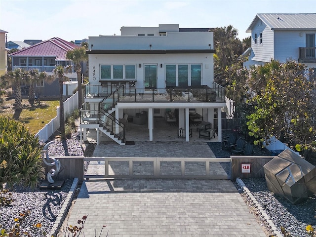 rear view of property featuring fence private yard, a garage, stairway, decorative driveway, and a patio area