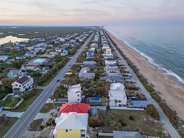 aerial view at dusk with a water view and a beach view