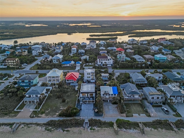 aerial view at dusk featuring a water view and a residential view