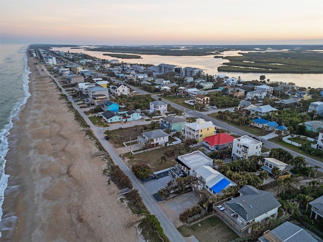 aerial view at dusk featuring a beach view and a water view