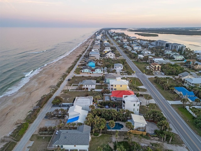 aerial view at dusk with a water view and a beach view