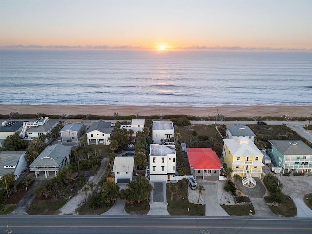 aerial view at dusk with a beach view, a water view, and a residential view