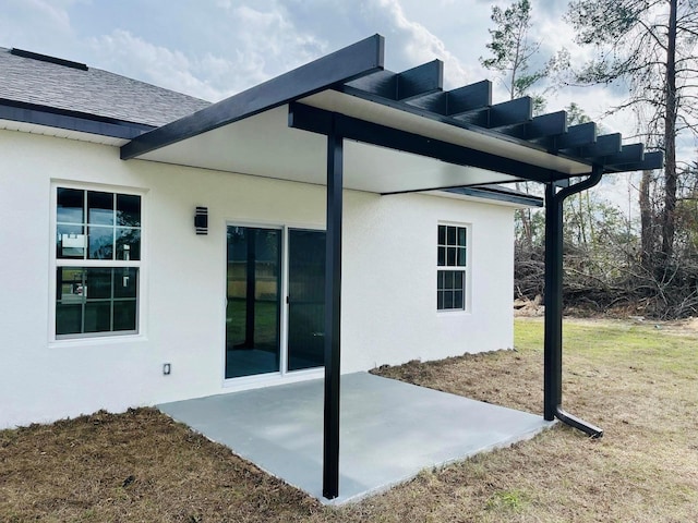 exterior space featuring roof with shingles, a patio, a lawn, and stucco siding