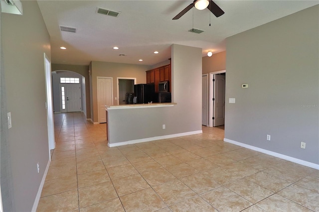1862 Great Falls Way, Orlando, FL 32824 - kitchen with freestanding refrigerator, light tile patterned floors, stainless steel microwave, arched walkways, and ceiling fan