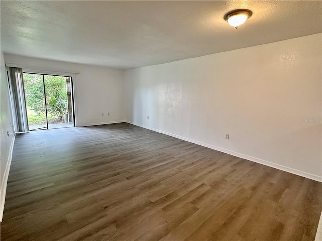 empty room featuring baseboards, a textured ceiling, and dark wood-style floors