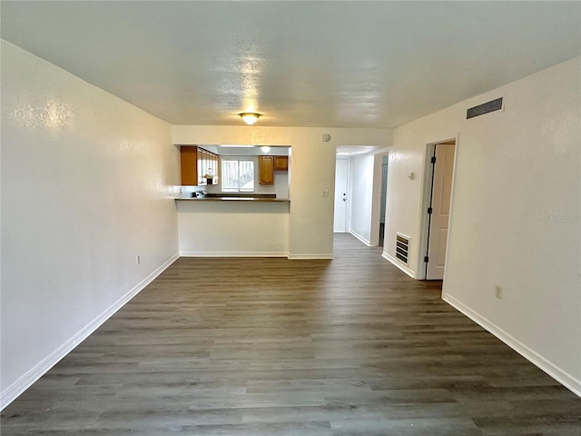 unfurnished living room with visible vents, baseboards, and dark wood finished floors