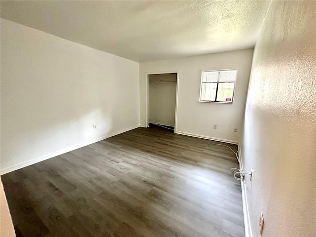 unfurnished bedroom featuring dark wood-type flooring, baseboards, and a textured ceiling