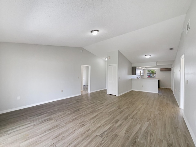 unfurnished living room featuring vaulted ceiling, baseboards, visible vents, and light wood-style floors