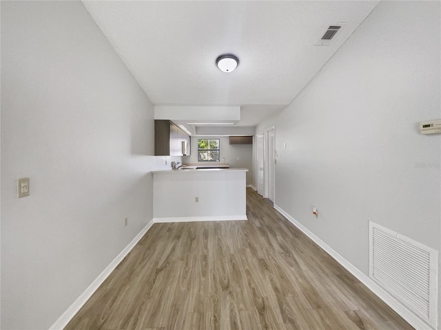 unfurnished living room featuring light wood-type flooring, baseboards, and visible vents